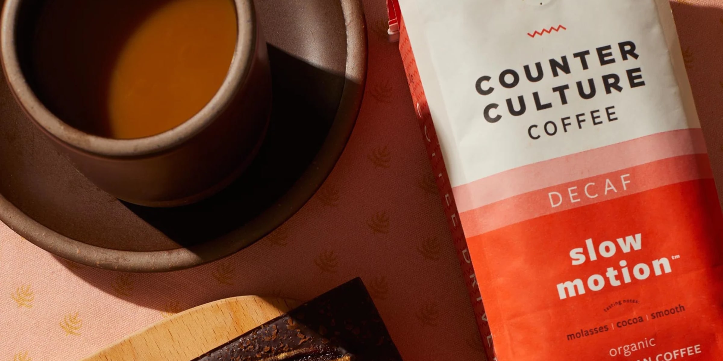 A top-down photograph of a cup of black coffee and a bag of decaffeinated coffee beans.